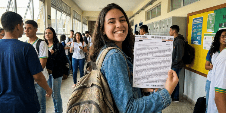 Estudante exibe folha de redação do ENEM em corredor de escola.