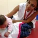 Profissional da saúde realiza atendimento em uma criança pequena em ambiente de reabilitação, exemplo do trabalho desenvolvido em áreas como Fisioterapia e Terapia Ocupacional.