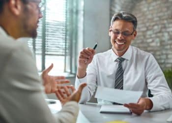 Recrutador conversa com candidato sobre competências para vaga de emprego.