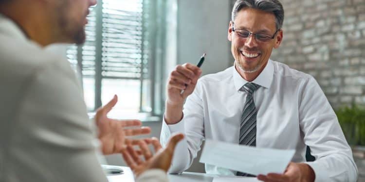 Recrutador conversa com candidato sobre competências para vaga de emprego.