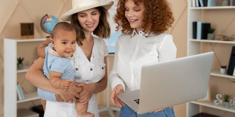 Mãe com bebê no colo conversa com consultora de carreira que mostra oportunidades de trabalho flexível em um notebook