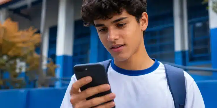 Estudante consultando no celular informações sobre os pagamentos do Pé-de-Meia liberados em maio