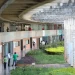 Vista do corredor de um campus universitário com estudantes caminhando entre os blocos de salas de aula, ilustrando a lista de cursos com pouca leitura no ensino superior