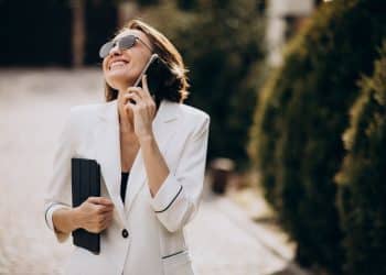 Mulher sorrindo enquanto fala ao celular em ambiente externo