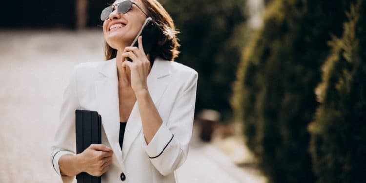 Mulher sorrindo enquanto fala ao celular em ambiente externo