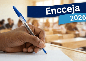 Mão escrevendo com caneta azul em papel durante prova, com texto “Encceja 2026” sobreposto à imagem de sala de aula.