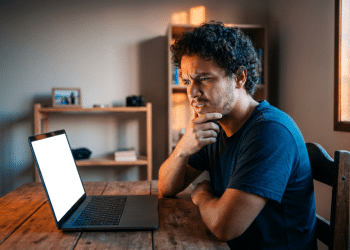 Homem observa a tela do notebook com expressão de dúvida