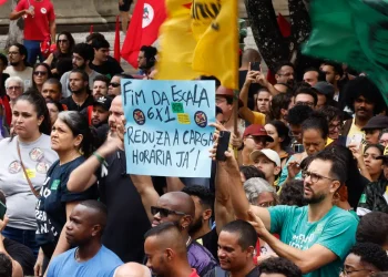 Manifestantes em ato público erguendo cartaz com a frase fim da escala 6x1 reduza a carga horária já.