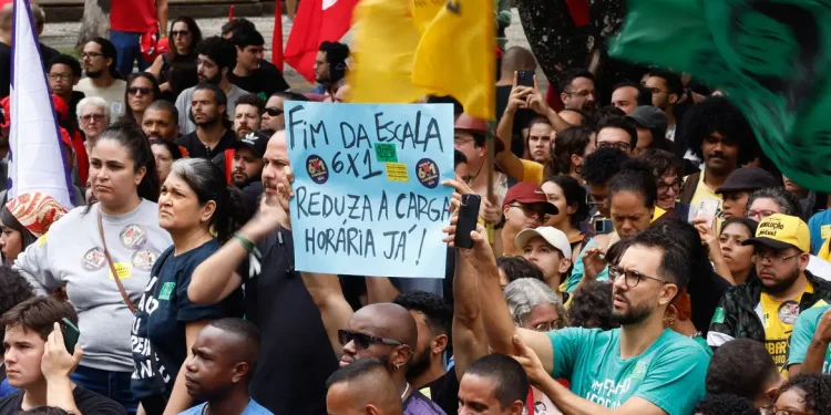 Manifestantes em ato público erguendo cartaz com a frase fim da escala 6x1 reduza a carga horária já.