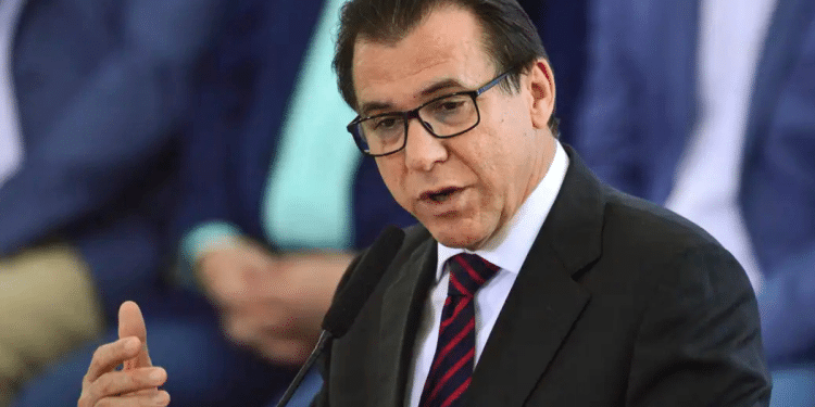 Ministro Luiz Marinho gesticula durante discurso, usando terno preto, gravata listrada vermelha e azul, e óculos.