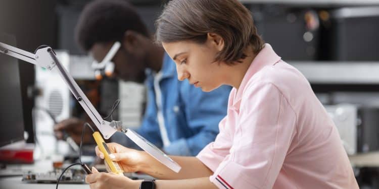 Formações para quem sai do ensino médio: jovem realiza atividade prática com instrumento de medição em laboratório, ao lado de colega trabalhando com microscópio