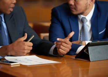 Dois profissionais do Direito conversando durante atendimento jurídico em escritório, em referência ao trabalho realizado pelos defensores públicos no Brasil