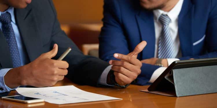 Dois profissionais do Direito conversando durante atendimento jurídico em escritório, em referência ao trabalho realizado pelos defensores públicos no Brasil