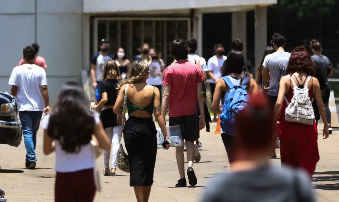 Grupo de jovens estudantes universitários caminhando em direção ao prédio de uma faculdade, em referência aos 16 cursos para quem não gosta de ler