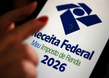 Mão com unhas vermelhas apontando para tela do celular exibindo logo da Receita Federal e Meu Imposto de Renda 2026.