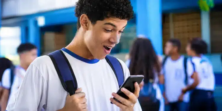 Estudante do ensino médio consultando no celular o benefício do Pé-de-Meia, representando a gratuidade no Enem 2026 e o incentivo extra de R$ 200.