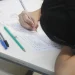 Jovem estudante concentrada escreve em folha de prova sobre carteira escolar em imagem ilustrativa sobre as novas regras do Enem 2026