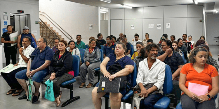Pessoas aguardam atendimento sentadas em sala de espera de agência do INSS, perto do setor de perícia médica.