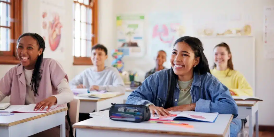 Estudantes sorrindo em sala de aula durante momento de aprendizagem sobre a origem da palavra escola
