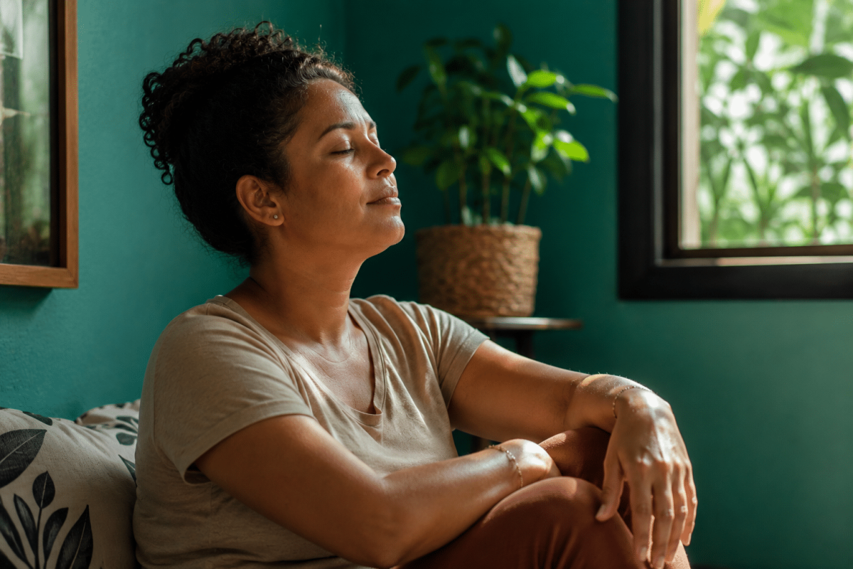 Mulher de olhos fechados relaxa sentada em um ambiente tranquilo de casa
