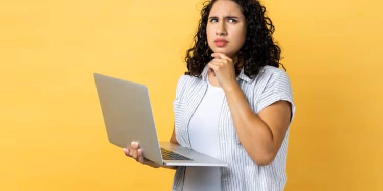 Mulher pensativa segurando notebook