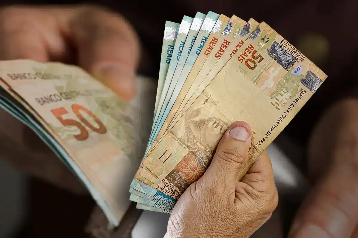Pessoa segurando notas de R$ 50, representando um dos três pagamentos extras em 2026, que é o ressarcimento das cotas do PIS/PASEP