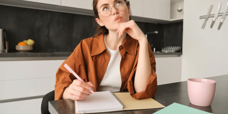 Mulher escrevendo em um caderno e pensando