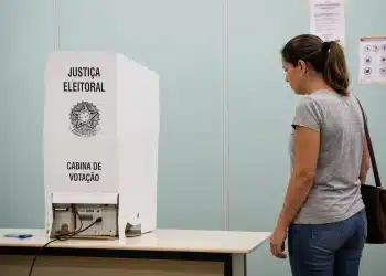 Eleitora diante de cabine de votação da Justiça Eleitoral em local de votação