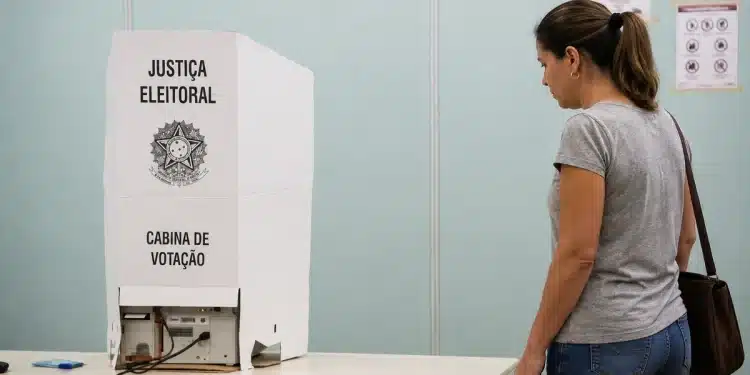 Eleitora diante de cabine de votação da Justiça Eleitoral em local de votação
