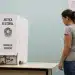 Eleitora diante de cabine de votação da Justiça Eleitoral em local de votação