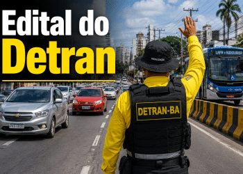 Agente do DETRAN-BA com colete amarelo e chapéu de fiscalização ergue a mão para orientar veículos em avenida de Salvador
