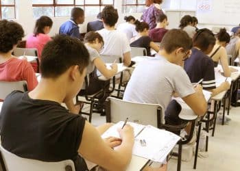 Estudantes sentados em carteiras escolares realizam as provas do Enem em uma sala de aula