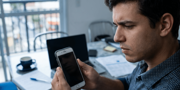 Homem observa o celular com expressão preocupada