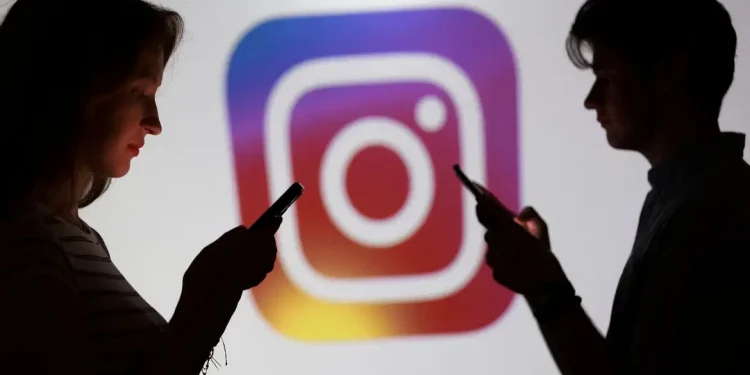 Silhuetas de uma mulher e um homem usando smartphones em frente ao logotipo colorido do Instagram, representação dos recursos de segurança ampliados pela Meta para usuários menores de idade.