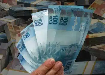 Cédulas de 100 reais em destaque representando o pagamento de R$ 1.621 do Programa de Integração Social, disponível para saque