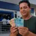 Trabalhador brasileiro segurando notas de real em frente a agência bancária, simbolizando o saque residual do FGTS liberado para milhões de beneficiários em maio de 2026.