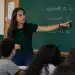 Professora apontando para quadro com explicação sobre o uso correto de referente a, à ou ao durante aula de português.