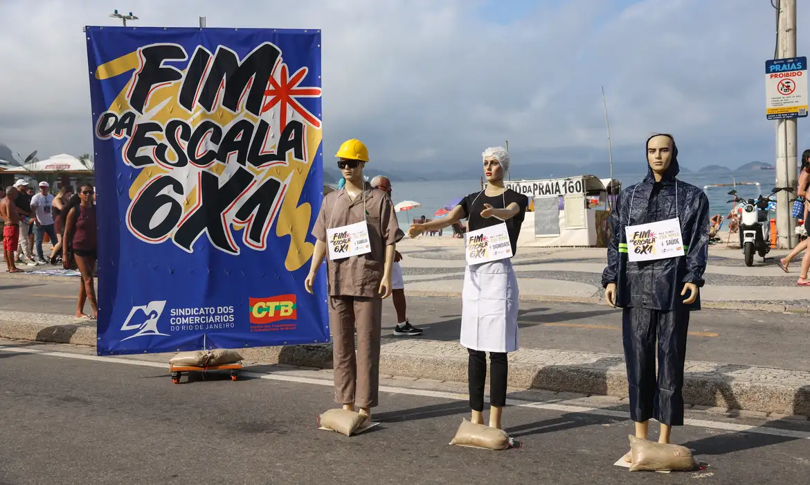 Manifestação pelo fim da escala 6x1 com manequins representando trabalhadores de diferentes categorias em frente a banner do Sindicato dos Comerciários
