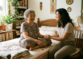 Idosa e mulher sorrindo juntas em quarto decorado com plantas e artesanato.