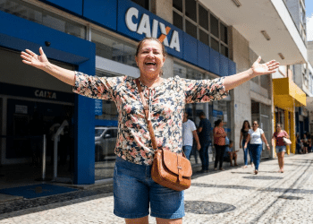 Mulher comemora em frente à Caixa Econômica após benefício liberado.