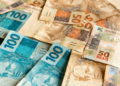 Notas de 50 e 100 reais representando dinheiro brasileiro em destaque.
