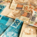 Notas de 50 e 100 reais representando dinheiro brasileiro em destaque.