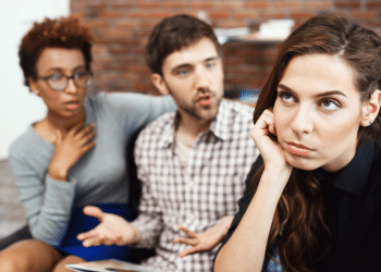 Conversa tensa entre três jovens, mulher expressa tédio em discussão.
