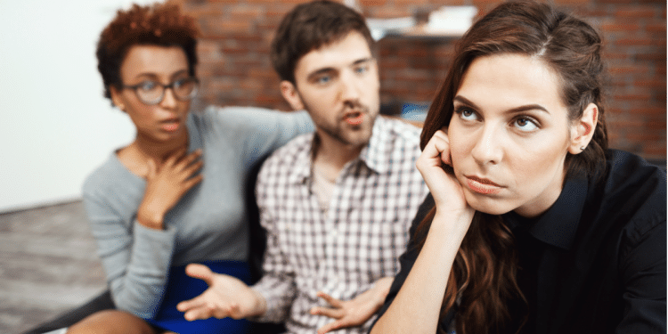 Conversa tensa entre três jovens, mulher expressa tédio em discussão.