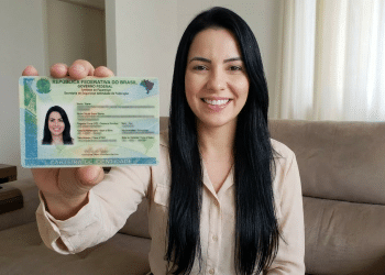 Mulher exibe nova carteira de identidade brasileira em casa.