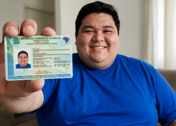 Homem sorridente exibe nova CIN em casa.