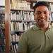 Homem segurando livros em biblioteca, representando estudante que pode ingressar em curso técnico com certificação do Encceja.