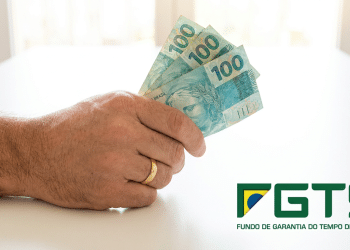 Trabalhador segura notas de R$100 com logo do FGTS ao lado.