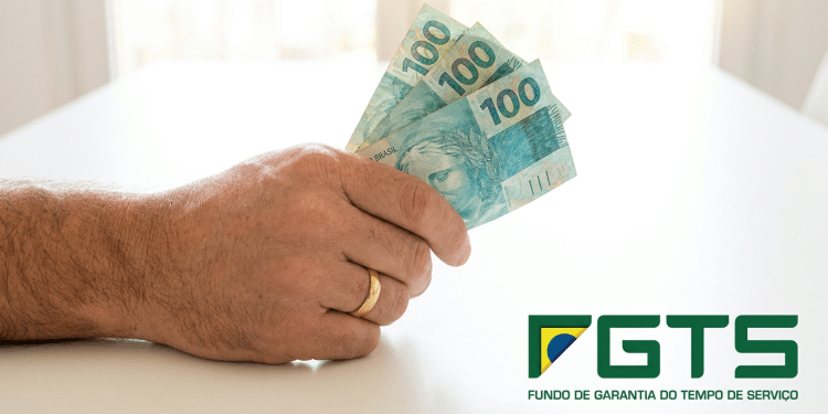 Trabalhador segura notas de R$100 com logo do FGTS ao lado.