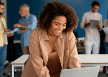 Jovem sorrindo trabalhando em equipe em escritório moderno.